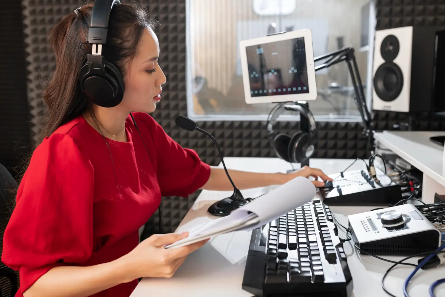 A woman in a red shirt is recording voice-over in a professional sound studio, illustrating audio marketing strategies for effective campaigns.