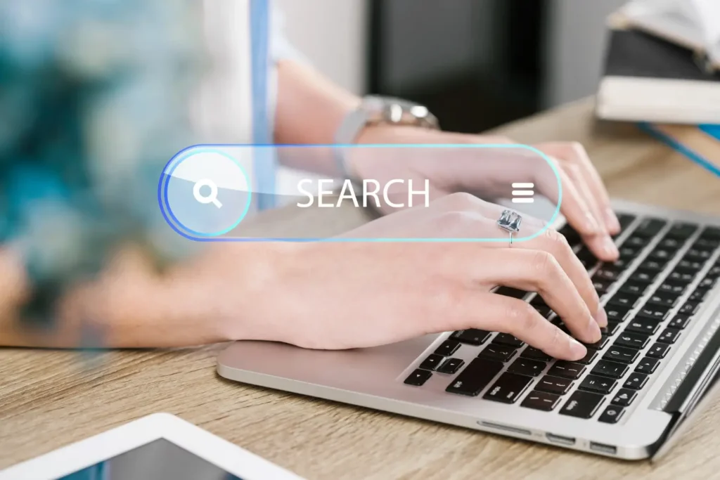 Hands typing on a laptop with a digital search bar overlay, symbolizing B2B keyword research and SEO optimization.
